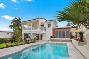 A modern backyard with large white paving slabs and artificial turf, illustrating professional home improvements for outdoor living spaces.