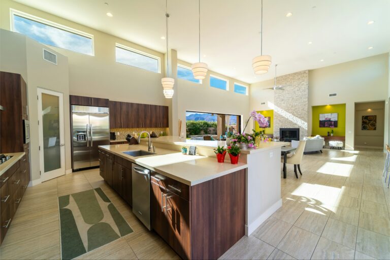 In this layout, the kitchen island becomes the central feature that separates and connects both spaces at the same time. Instead of a wall, the island defines the kitchen area while maintaining openness toward the living room. It also adds seating, storage, and additional workspace, making it one of the most practical and widely used designs. This approach works especially well in homes where the kitchen is being updated as part of a broader remodel.