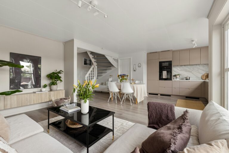 Open concept remodel with living area, connecting dining space, and modern kitchen with taupe cabinets and marble-style backsplash.
